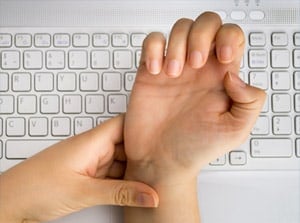 A close-up of a hand making the fist gesture over a white computer keyboard, symbolizing startup, control, or emphasis in a tech or business setting.