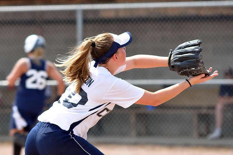 A female softball player catches an incoming ball